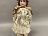 poupée en porcelaine représentant une jeune fille vêtue d'une robe blanche et d'un bonnet