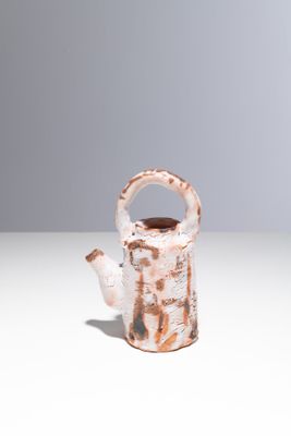 un petit vase muni d'une anse, posé sur une table