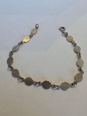 gros plan d'un bracelet en argent sur une surface blanche