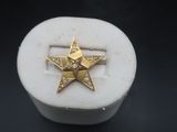 une image représentant une bague en forme d'étoile dorée posée sur une boîte blanche