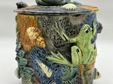 a ceramic container with a frog and other animals on it