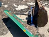 a green plow sitting on the ground next to a pile of wood