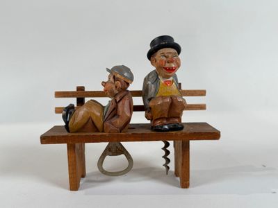 figurines of two men sitting on a bench with a bottle opener