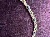 bracelet composé de perles en or et en verre bleu, montées sur un fond de velours violet