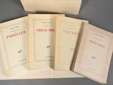 four books are sitting on a table with a box in the background