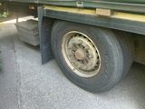 a truck with a flat tire and a brush on the side of the road