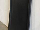 black door with a hole in the middle of it next to a white wall