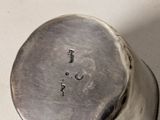 a silver pepper shaker on a white surface