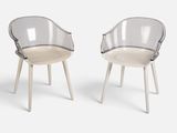 deux chaises en plastique transparent avec des pieds en bois, posées sur une surface blanche