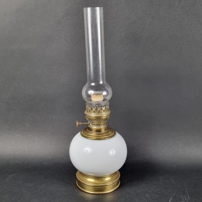 an old fashioned oil lamp with a glass shade on top of it