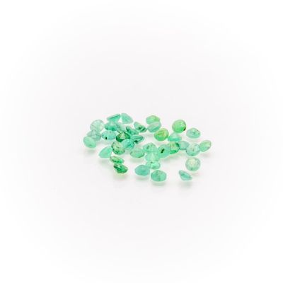 a pile of green emeralds on a white surface