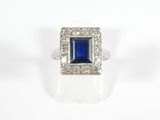 a close up of a ring with a blue stone surrounded by diamonds