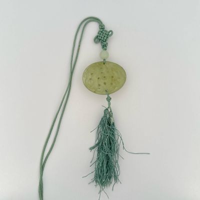 a necklace with a green tassel hanging from it ' s side