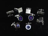 many different types of cufflinks on a black surface