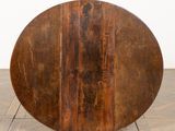 an old wooden table with a round top sitting on a wooden floor