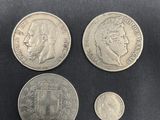 four different coins on a black cloth with a black background