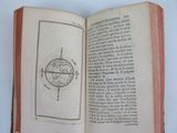 someone is holding an open book with a drawing of a compass on it