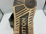 la semelle d'une paire de chaussures noires et dorées posée sur une surface blanche