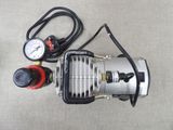 a small air compressor sitting on the floor next to a pressure gauge