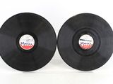 two black vinyl records sitting on top of each other on a white surface