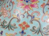 a hand holding a blue vase with a floral design on it