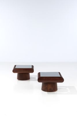 a pair of wooden stools with a glass top on a white surface