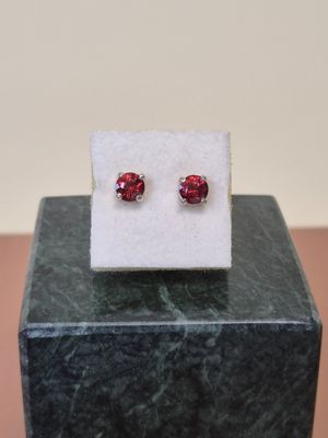 a pair of red earrings sitting on top of a marble block