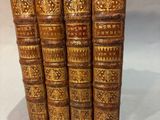 a set of five old books with gold covers on a white surface