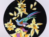 une assiette noire décorée d'un oiseau et de fleurs colorés