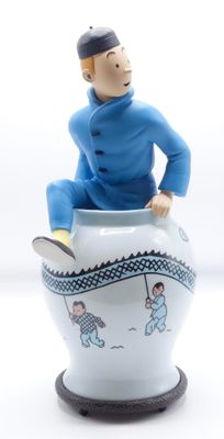 une figurine représentant un homme assis sur une tasse