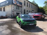 a green car parked in front of a building in a parking lot