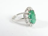 an oval emerald and diamond ring on a white background