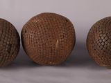 Trois boules en bois sont posées les unes à côté des autres sur une surface blanche