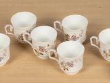 six cups and a saucer sitting on a table