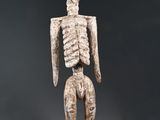 une statue représentant un squelette posé sur un socle en bois