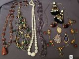 many different necklaces and bracelets that are on a table