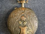 an old gold pocket watch with a floral design on it