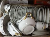 a box full of white and gold china plates and bowls