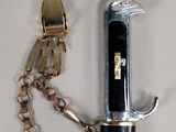 a knife with a chain attached to it on a white surface