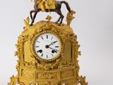 une horloge en or surmontée d'une statue représentant un homme à cheval