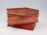 three old books stacked on top of each other on a white surface