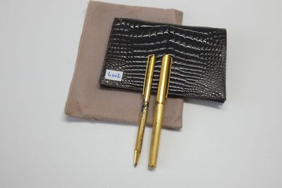 deux stylos et un portefeuille posés sur une surface blanche