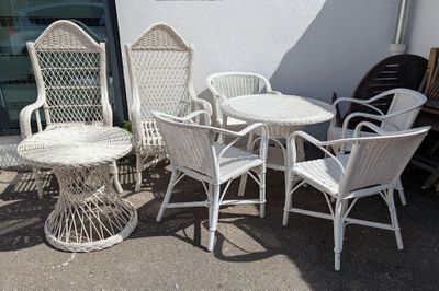 plusieurs chaises en osier blanc et une table à l'extérieur d'un bâtiment