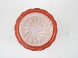 a red glass bowl with a white lid on a white table