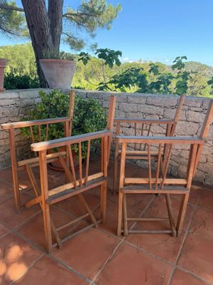 three wooden chairs sitting on a brick patio next to a tree