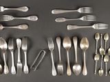 un grand nombre de cuillères et de fourchettes disposées sur la table