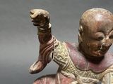 statue of a man sitting on a rock holding a knife