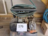 un petit compresseur d'air posé par terre à côté d'un tas de bois