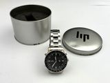a watch sitting next to a tin of coffee on a table