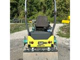 a close up of a road roller on gravel with trees in the background
